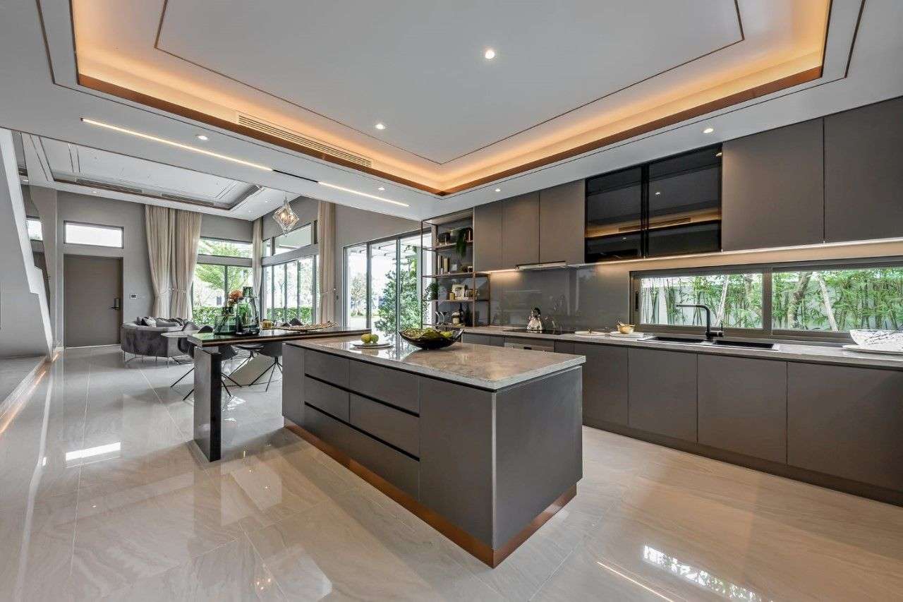 Thi Công Nội Thất Phòng Bếp 22 Thiết kế bếp cao cấp với đảo trung tâm ốp đá marble và hệ tủ tối màu hiện đại, mở rộng tầm nhìn ra sân vườn