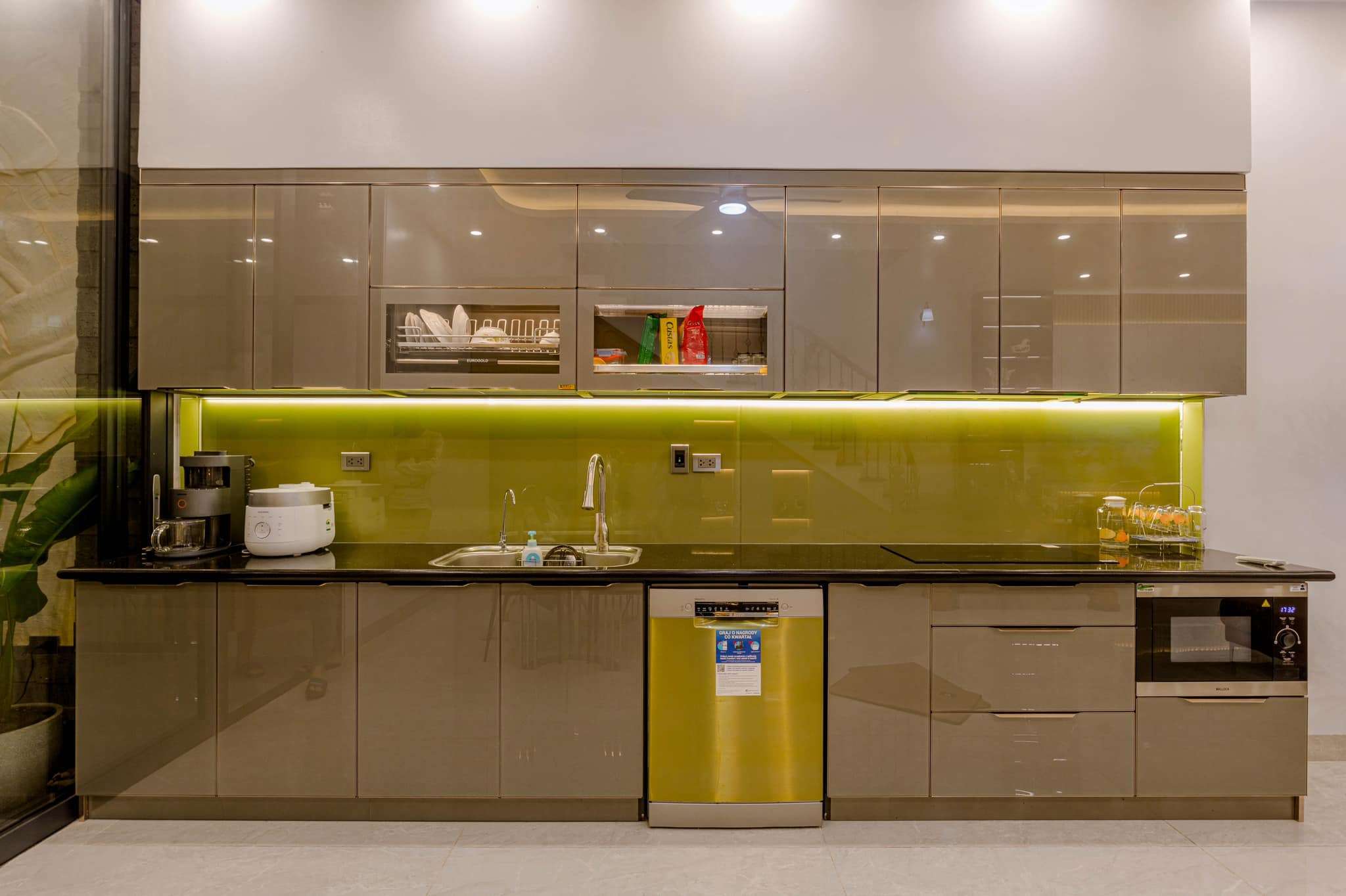 Thi Công Nội Thất Chung Cư 46 Tủ bếp cánh kính màu olive hiện đại với backsplash kính màu xanh lá non