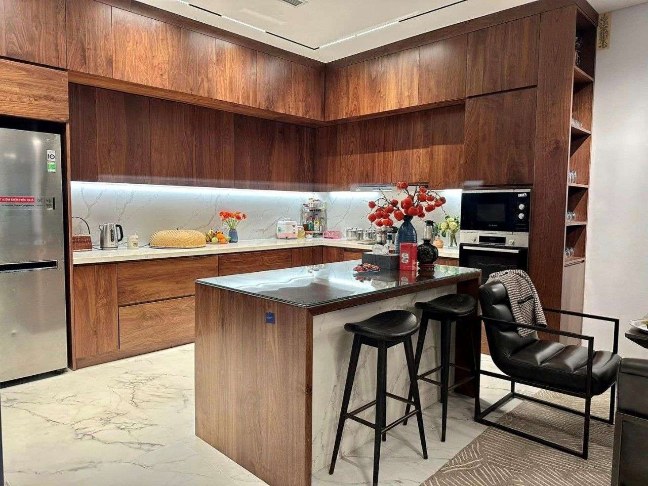 Thi Công Nội Thất Phòng Bếp 29 Khu bếp cao cấp tích hợp quầy bar và bàn ăn liền mạch với hệ đèn thả thanh mảnh hiện đại